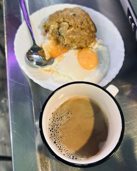 A bolón de verde with a fried egg and a cup of coffee on the bar counter.