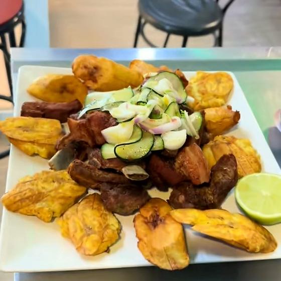 Fried meat with patacones, pickled cucumber and red onion.